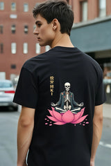 Person wearing a black t-shirt with a skeleton and lotus design on the back, standing on a street.